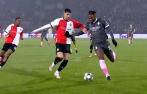 Jakub Moder w barwach Feyenoordu odbiera piłkę zawodnikowi AC Milan podczas meczu Ligi Mistrzów. Polski pomocnik dynamicznie wybija futbolówkę spod nóg rywala.