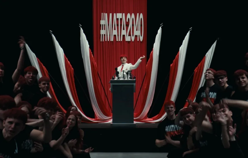 Mata przemawiający z mównicy na tle biało-czerwonych flag z hasłem #MATA2040 - kadr z teledysku Będę prezydentem :)