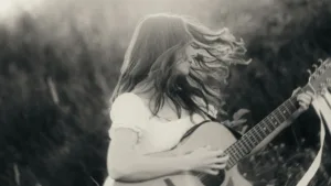 Aga Laura grająca na gitarze w plenerze - kadr promujący singiel Zwiedzam Świat