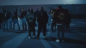 Bone Thugs-N-Harmony idą nocą w grupie na tle kontenerów przemysłowych - kadr z teledysku Road Nights