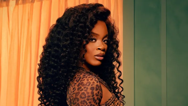 Ari Lennox w stylowej stylizacji, z długimi kręconymi włosami promująca album Vacancy