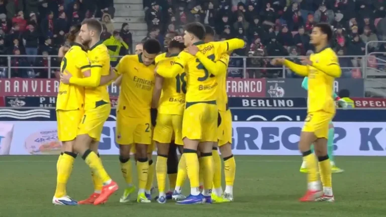 Piłkarze AC Milan w żółtych strojach celebrują zdobycie bramki, obejmując się na boisku podczas meczu Serie A z Bologną.