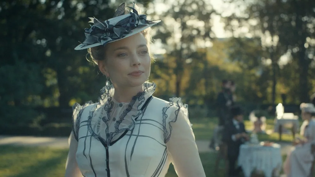 Kadr z teasera filmu Lalka - Izabela Łęcka w eleganckiej sukni z XIX wieku podczas spaceru w ogrodzie