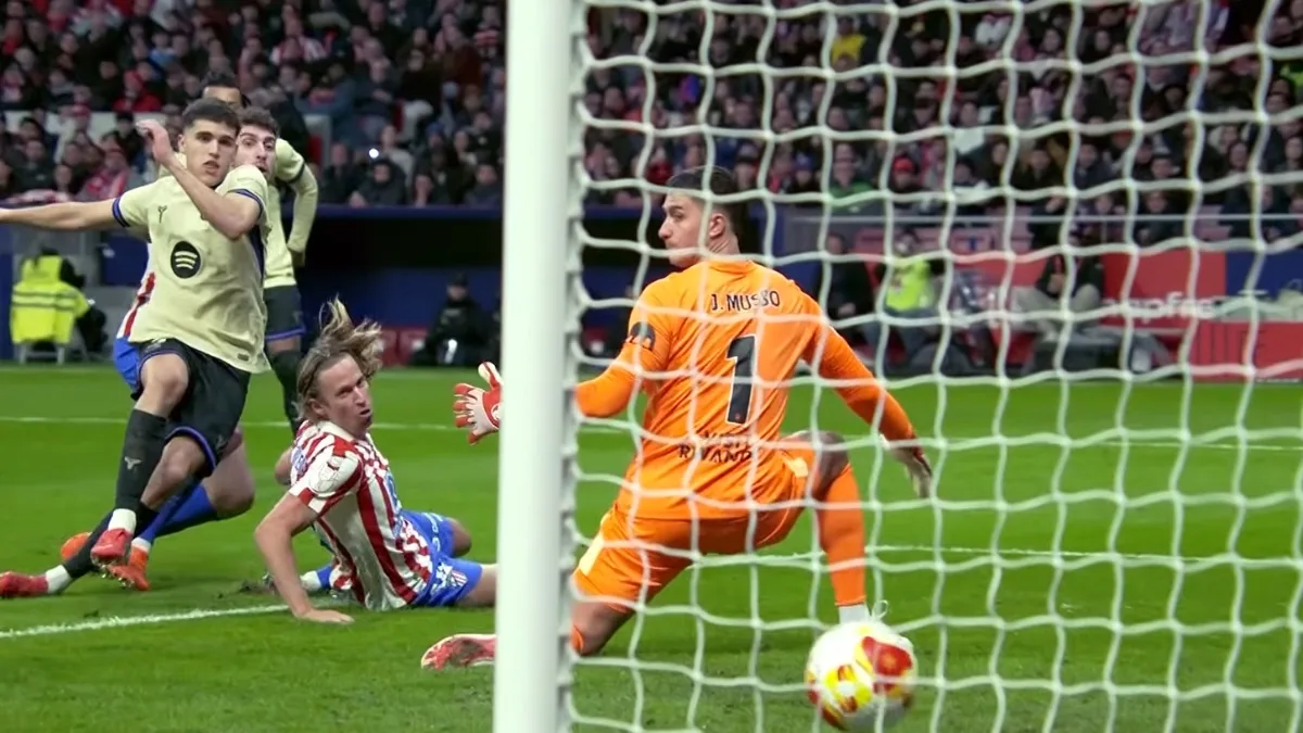 Strzał piłkarza Barcelony w polu karnym Atlético, Juan Musso broni bramki.