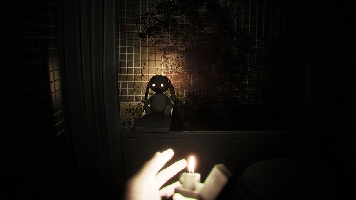 Mroczna łazienka z gry Dread Neighbor oświetlona świecą, na tle zakrwawionej ściany siedzi lalka z świecącymi oczami, widok z perspektywy pierwszej osoby.