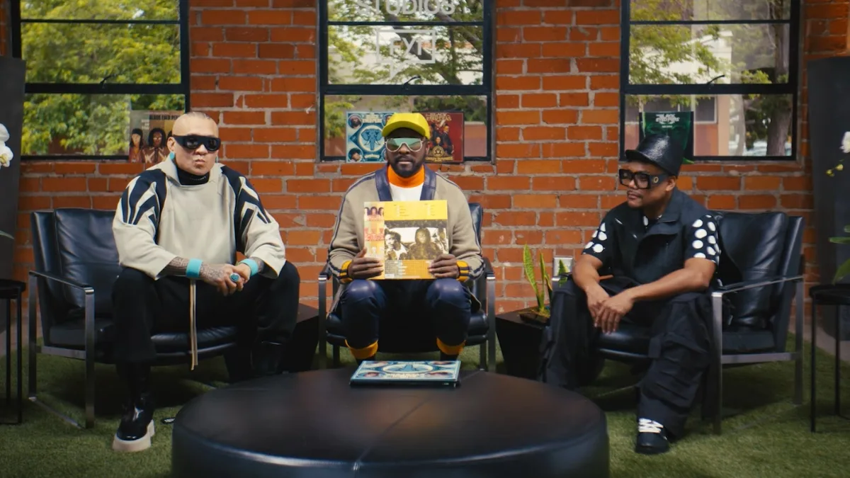 Black Eyed Peas w studiu nagraniowym na tle ceglanej ściany; członkowie zespołu siedzą z winylową płytą - artyści ogłoszeni jako headliner Warsaw Music Festival 2026.