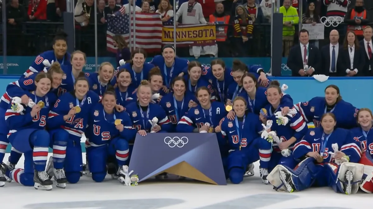 Reprezentacja USA w hokeju kobiet po zdobyciu złotego medalu na Zimowych Igrzyskach Olimpijskich Mediolan-Cortina 2026, zawodniczki pozują na lodzie z medalami.