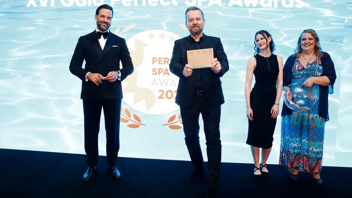 Prowadzący i laureaci stoją na scenie podczas XVI Gali Perfect SPA Awards 2026, jeden z mężczyzn prezentuje kopertę z wynikami, w tle widoczne logo wydarzenia.
