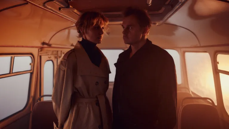 Bovska i Piotr Rogucki stoją naprzeciw siebie we wnętrzu autobusu skąpanego w ciepłym, pomarańczowym świetle; scena z teledysku London.