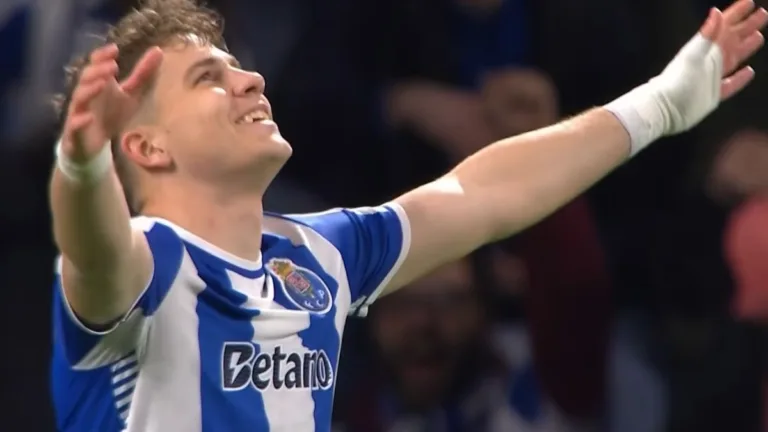 Oskar Pietuszewski w koszulce FC Porto z uniesionymi rękami celebruje gola, uśmiechnięty, patrzy w górę.