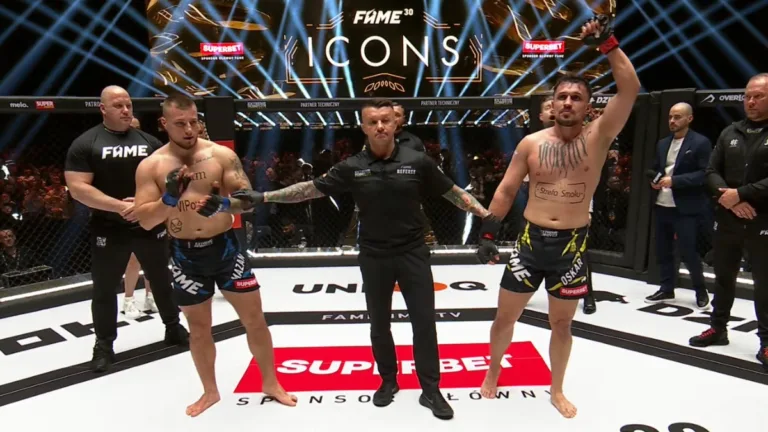 Oskar Wierzejski z uniesioną ręką po zwycięstwie nad Klaudiuszem "Mazanem" Mazanowskim podczas gali FAME 30: Icons w klatce MMA.
