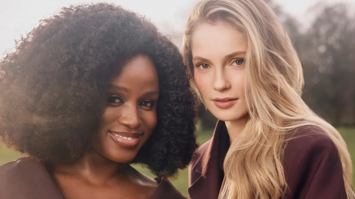 Bohaterki 5 sezonu serialu Bridgertonowie, Francesca i Michaela stoją razem w eleganckich strojach na tle parku, patrząc w obiektyw.